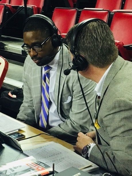 Kobie Baker courtside with a headset during a college basketball broadcast